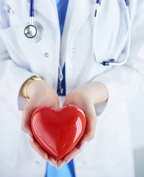 Medico femminile con stetoscopio che tiene il cuore, su sfondo chiaro — Foto Stock