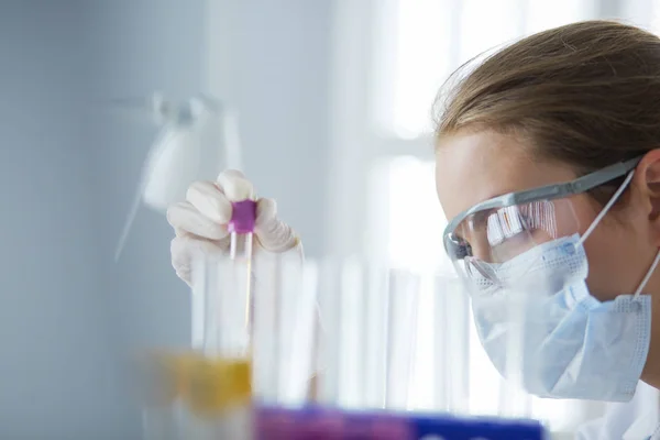 Un investigador médico o científico o un médico que observa un tubo de ensayo de solución verde líquida en un laboratorio —  Fotos de Stock