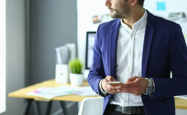 Retrato del joven diseñador frente a la computadora portátil y el ordenador mientras trabaja . — Foto de Stock