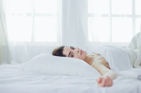 Pretty woman lying down on her bed at home — Stock Photo, Image