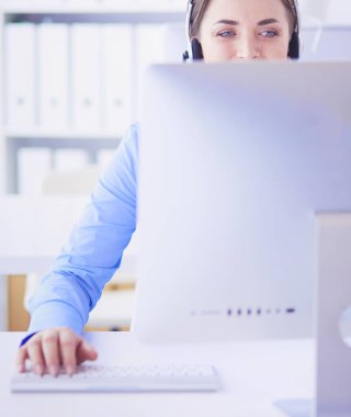 Ofisinde kulaklık takmış, telefon operatörü olarak çalışan ciddi ve güzel bir genç kadın.