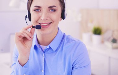 Ofisinde kulaklık takmış, telefon operatörü olarak çalışan ciddi ve güzel bir genç kadın.