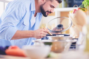 Dijital tablet ve yemek pişirme tarifine uyan bir adam evdeki mutfakta lezzetli ve sağlıklı yemekler pişiriyor.