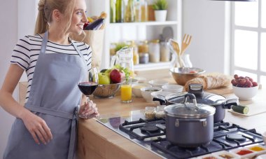 Güzel kadın mutfakta şarap içiyor.