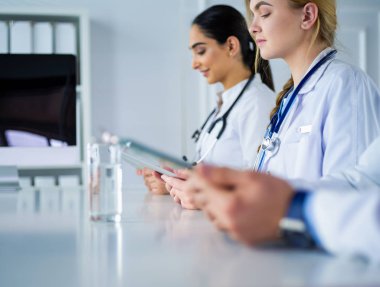 Toplantıdaki doktorlar, masanın üstünde oturuyorlar.