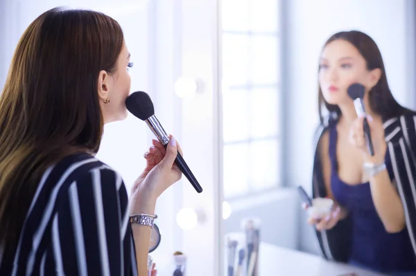 Belle fille regardant dans le miroir et appliquant cosmétique avec un gros pinceau — Photo