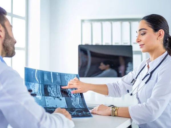 Deux médecins étudient l'image radiographique, consultant dans un bureau lumineux — Photo