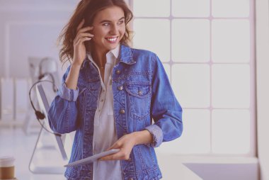 Gülümseyen kadın kahve içiyor ve kafede tablet kullanıyor.