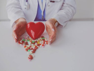 Masada kırmızı kalbi ve steteskopu olan kardiyolog.