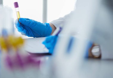 Kadın araştırmacı, beyaz arka planda izole edilmiş ilaç şişeleri ve mataralarla çevrili.