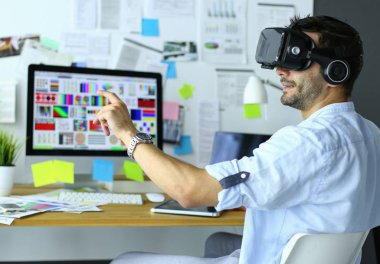 Genç erkek yazılım programcısı ofiste üç boyutlu sanal gerçeklik gözlükleriyle yeni bir uygulama test ediyor..