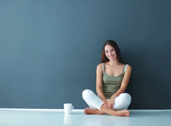 Una hermosa joven sana sentada en el suelo con una taza de té o café —  Fotos de Stock