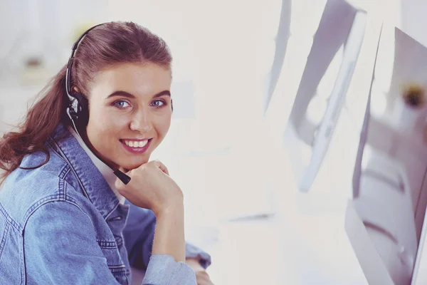 Retrato de una hermosa mujer de negocios trabajando en su escritorio con auriculares y portátil — Foto de Stock