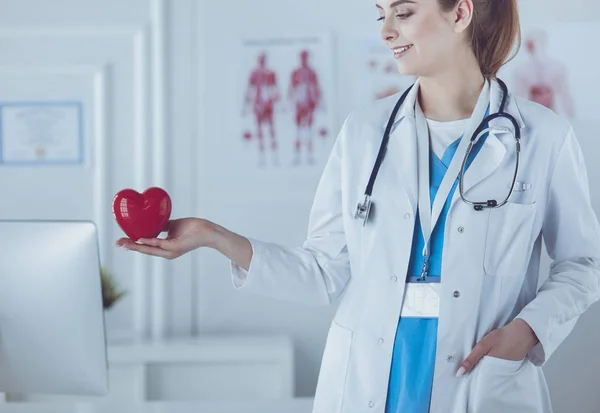 Ärztin mit Stethoskop, das Herz hält, auf hellem Hintergrund — Stockfoto