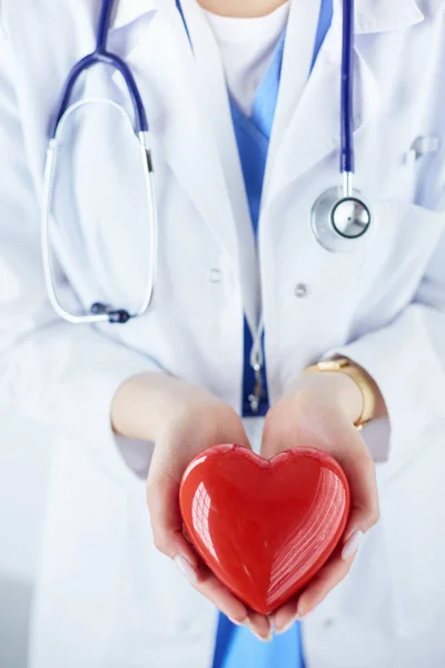 Doctora con estetoscopio sosteniendo el corazón, sobre fondo claro — Foto de Stock