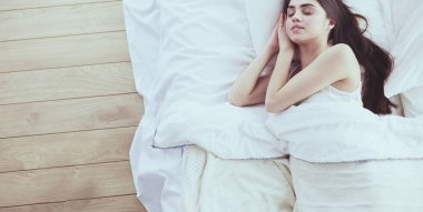 Güzel bir kadın yatağında uzanıyor.