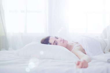 Güzel bir kadın yatağında uzanıyor.