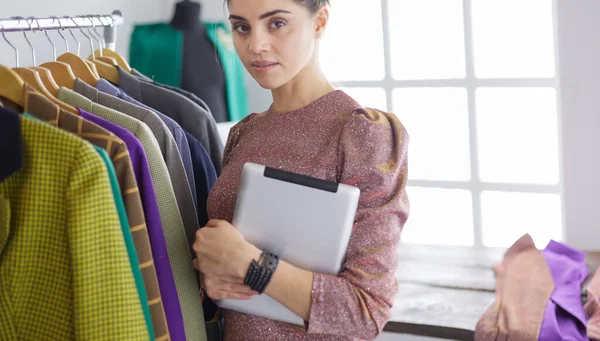 Mooie jonge stylist bij rek met hangers — Stockfoto