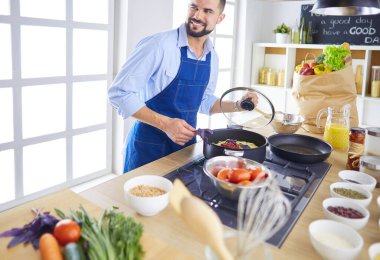 Adam ev mutfağında lezzetli ve sağlıklı yemekler hazırlıyor.