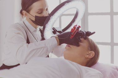 Mikro patenli kaşlar güzellik salonunda çalışır. Kaşları renkli bir kadın.