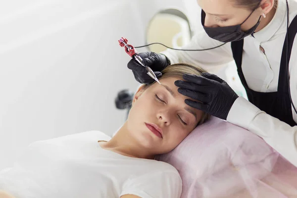Mujer joven sometida a procedimiento de maquillaje permanente de cejas en salón de belleza —  Fotos de Stock