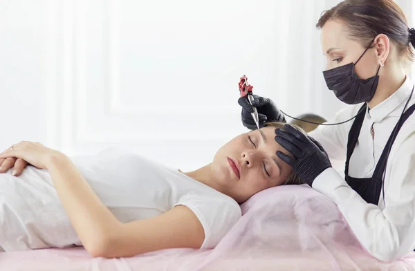 Mujer joven sometida a procedimiento de maquillaje permanente de cejas en salón de belleza — Foto de Stock