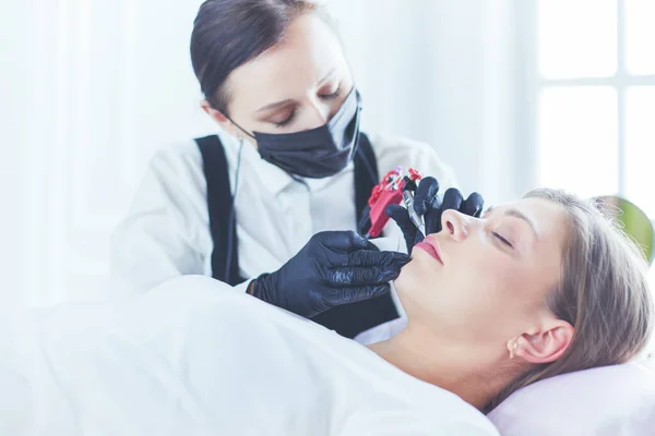 Cosmetólogo aplicando maquillaje permanente en las cejas —  Fotos de Stock