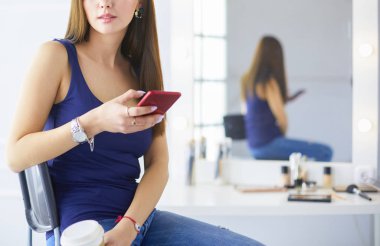 Kafede kahve içip cep telefonuyla konuşan genç bir kadın.