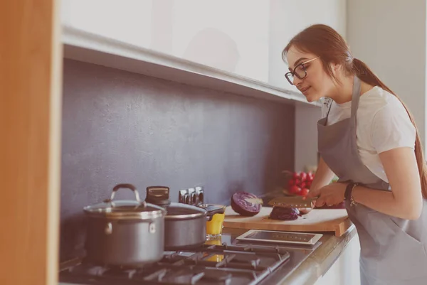 Mujer joven usando una tableta para cocinar en su cocina — Foto de Stock