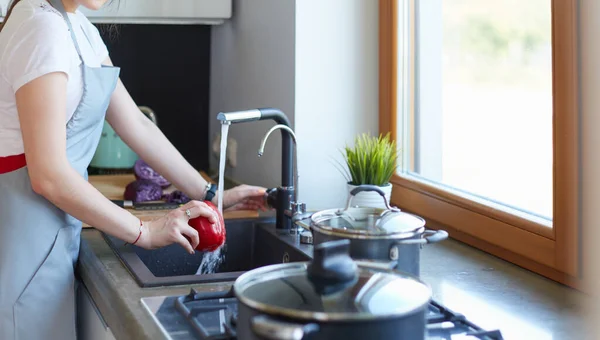 Donna che lava le verdure. Bella giovane donna che lava verdure per insalata e sorride mentre si trova in cucina — Foto Stock