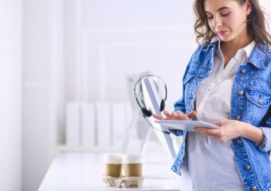 Gülümseyen kadın kahve içiyor ve kafede tablet kullanıyor.