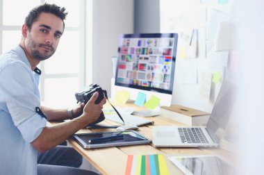 İnternette çalışırken bilgisayarın ve dizüstü bilgisayarın önünde grafik stüdyosunda oturan genç tasarımcının portresi.