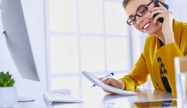 Retrato de una hermosa mujer haciendo una llamada mientras está sentada en su lugar de trabajo frente a la computadora portátil y trabajando en un nuevo proyecto — Foto de Stock