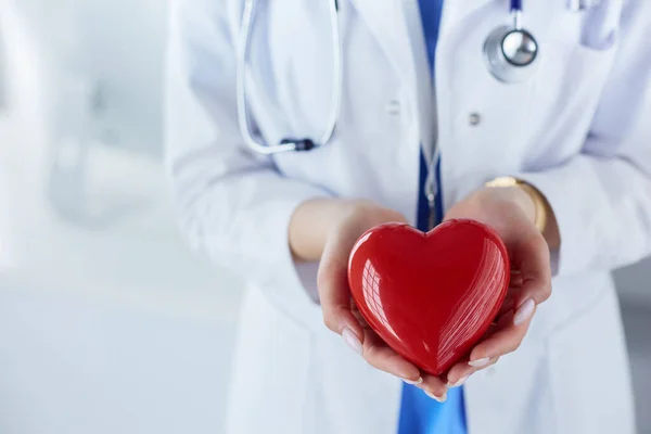 Steteskop tutan, kalbi hafif arka planda olan kadın bir doktor.