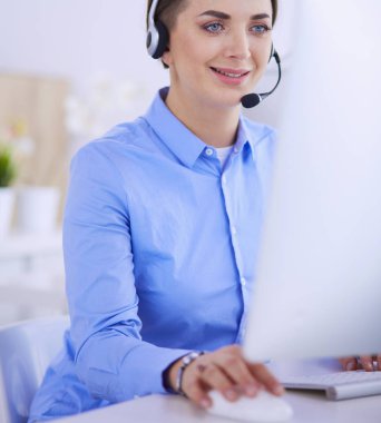 Ofisinde kulaklık takmış, telefon operatörü olarak çalışan ciddi ve güzel bir genç kadın.