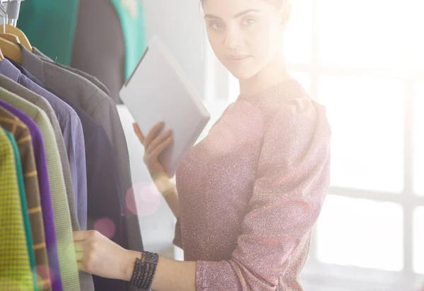 Mooie jonge stylist bij rek met hangers — Stockfoto