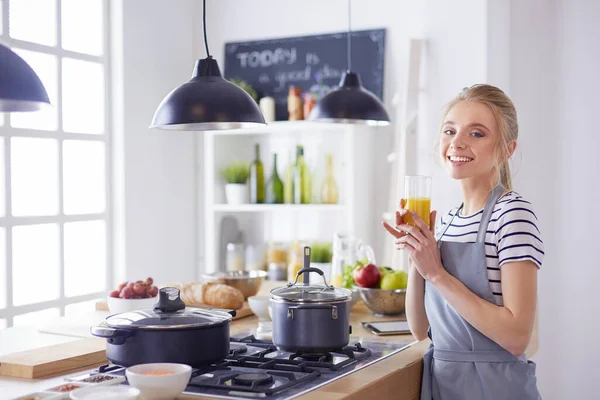 Mulher atraente segurando um copo de suco de laranja enquanto estava na cozinha — Fotografia de Stock