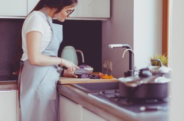 Masanın yanında duran mutfakta sebze doğrayan genç bir kadın.