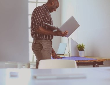 Ofiste bilgisayar ve planlarla çalışan Afrikalı Amerikalı bir mimar.