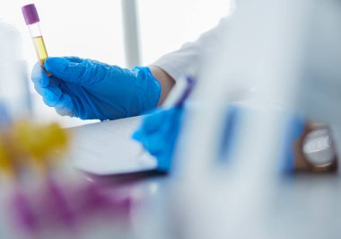 Kadın araştırmacı, beyaz arka planda izole edilmiş ilaç şişeleri ve mataralarla çevrili.