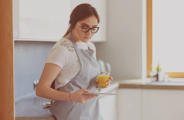 Молодая женщина с апельсиновым соком и таблетками на кухне — стоковое фото