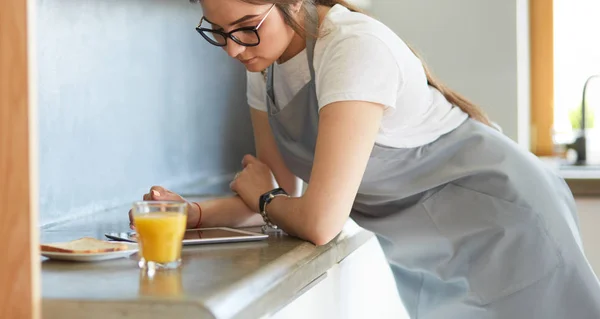 Ritratto di giovane attraente casalinga caucasica bruna in cucina. Mattina con tazza di caffè e tablet pc — Foto Stock