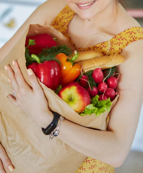 Ung kvinna som håller i matkassen med grönsaker — Stockfoto