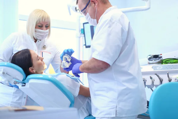 Mannelijke tandartsen onderzoeken en werken op jonge vrouwelijke patiënt.Tandartsen kantoor. — Stockfoto