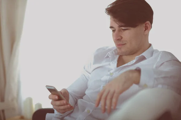 Pohledný mladý muž doma pomocí smartphonu — Stock fotografie