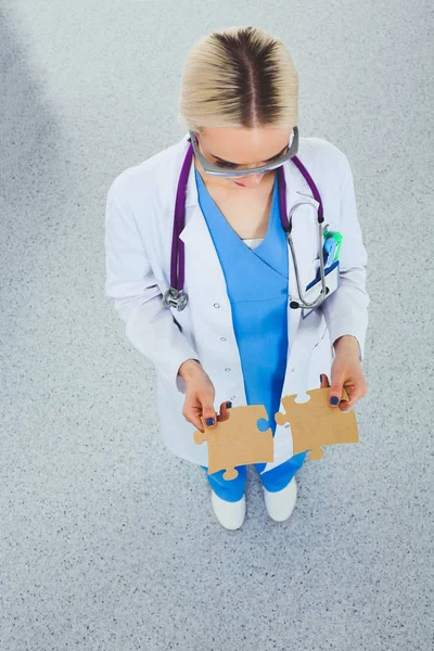Woman doctor holding two connecting puzzle pieces — Stock Photo, Image