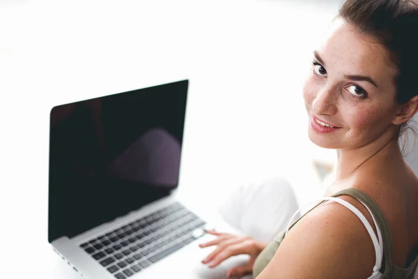 Eine junge Kollegin sitzt mit einem Laptop auf dem Boden — Stockfoto