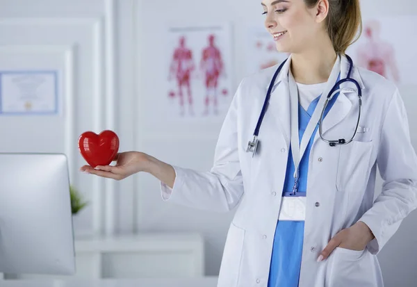 Kobieta-lekarz ze stetoskopem trzymającym serce, na jasnym tle — Zdjęcie stockowe