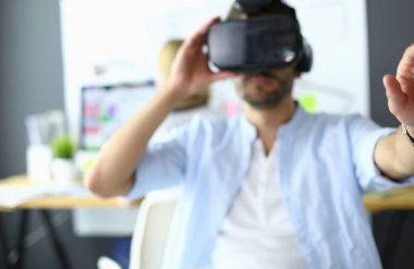 Genç erkek yazılım programcısı ofiste üç boyutlu sanal gerçeklik gözlükleriyle yeni bir uygulama test ediyor..