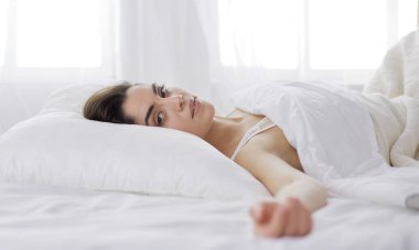 Güzel bir kadın yatağında uzanıyor.